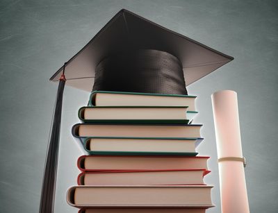Graduation cap over the pile of books with blackboard on background. Clipping path included, Foto: Kiyoshi Takahase Segundo / Colourbox