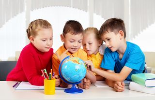 Vier Kinder erkunden gemeinsam einen Globus.