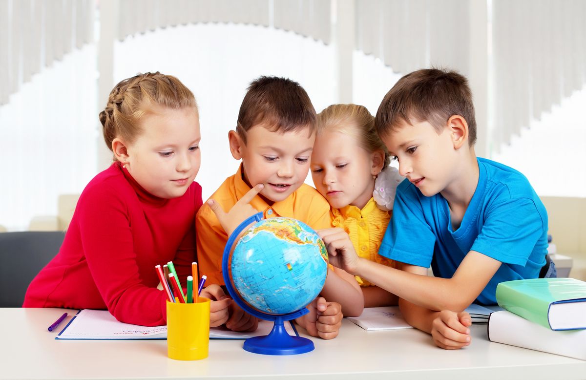 zur Vergrößerungsansicht des Bildes: Vier Kinder erkunden gemeinsam einen Globus.