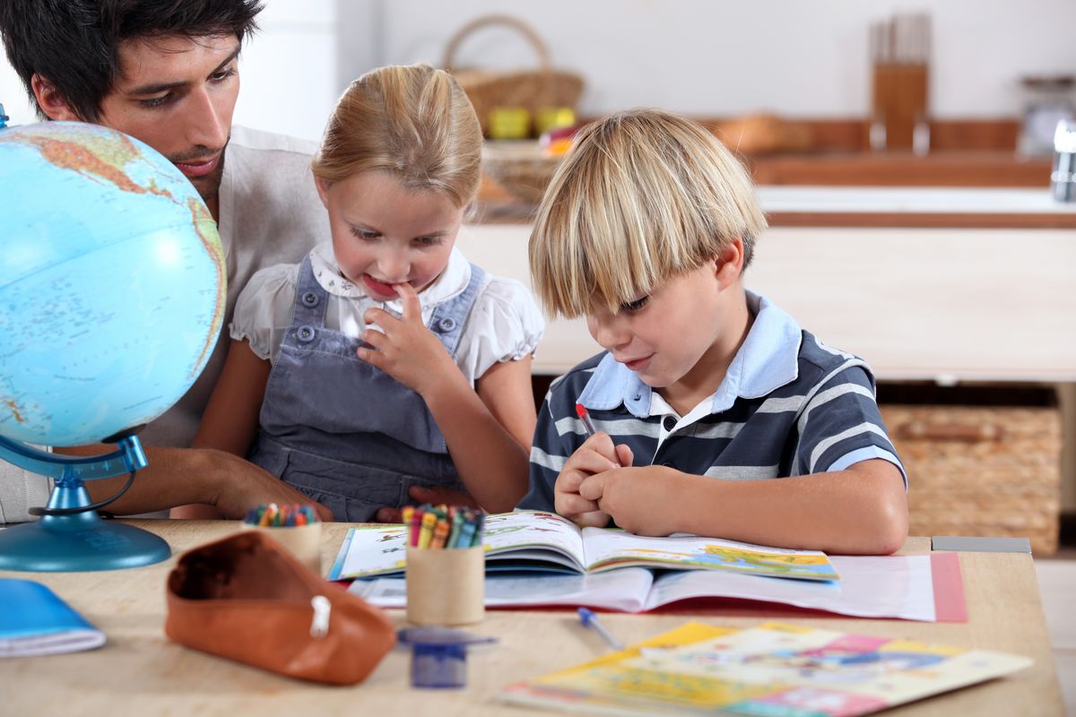 zur Vergrößerungsansicht des Bildes: Lehrer an einem Tisch mit zwei Grundschulkindern