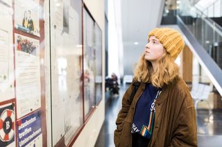 Studentin schaut in einen Schaukasten im Hörsaalgebäude, Foto: Christian Hüller