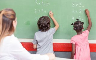 Zwei Kinder lösen an einer Tafel Matheaufgaben