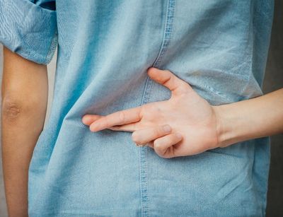 Kind hält Hand mit gekreuzten Fingern hinter dem Rücken