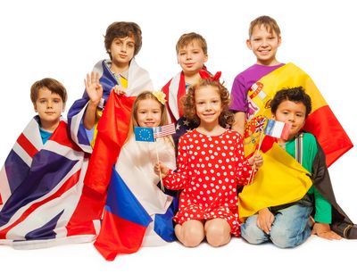 Gruppenfoto vieler Kinder, die unterschiedliche Nationalflaggen um die Schultern tragen.