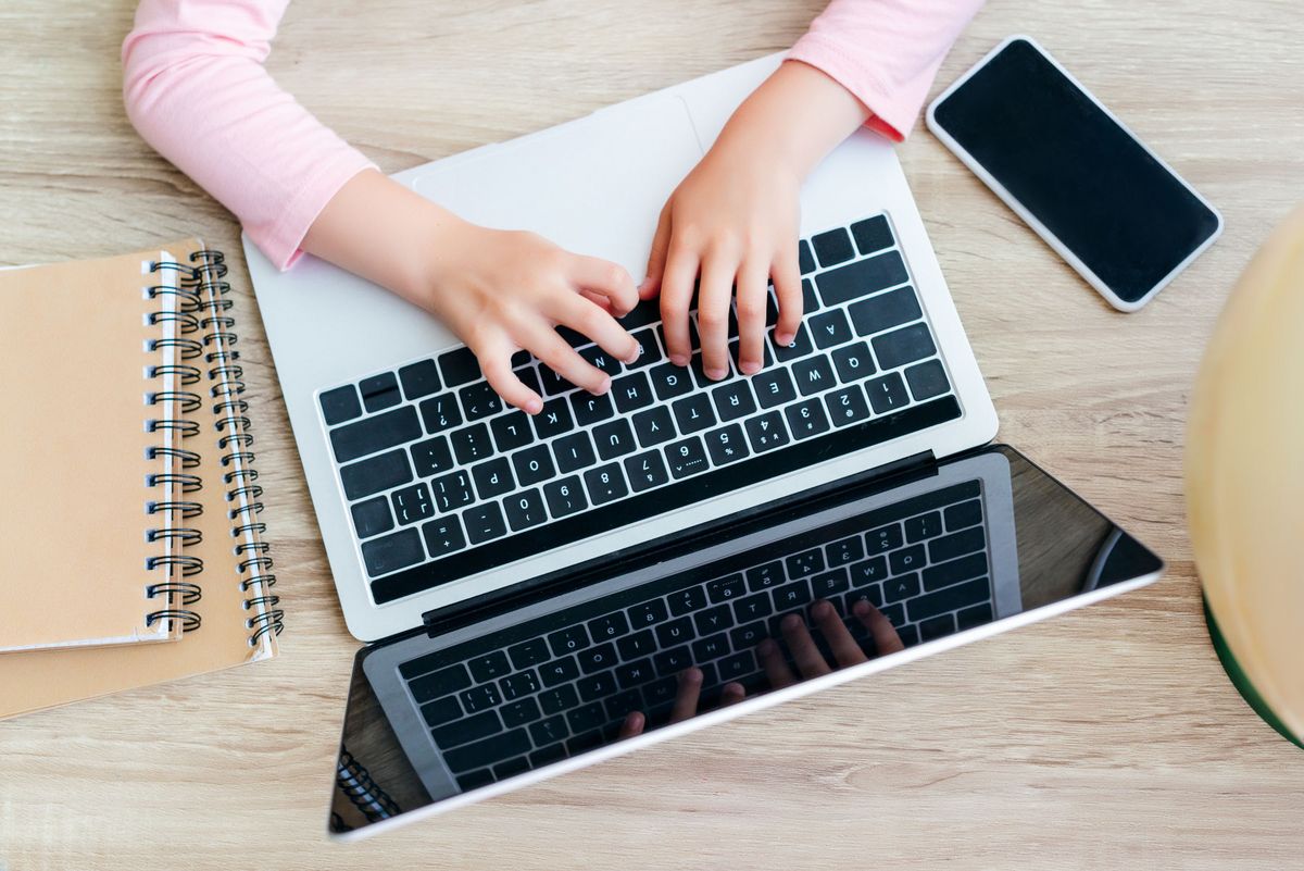 enlarge the image: A girl is working on a laptop.