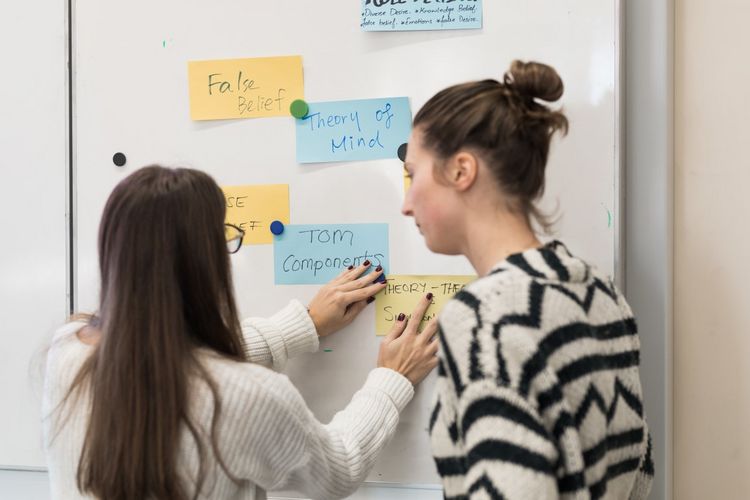 Students hang their index cards on a board with magnets