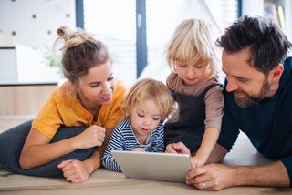Eltern schauen mit Kindern auf ein Tablet