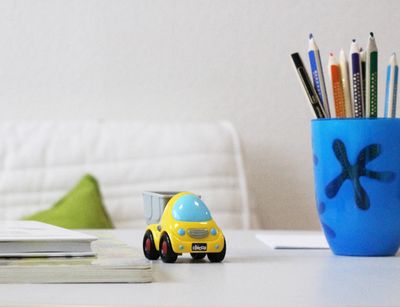 Farbfotografie eines Schreibtisches mit einem Spielzeugauto und einer Stiftebox