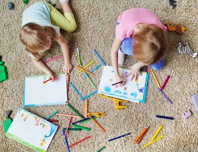 zwei Kinder liegen auf dem Boden und malen