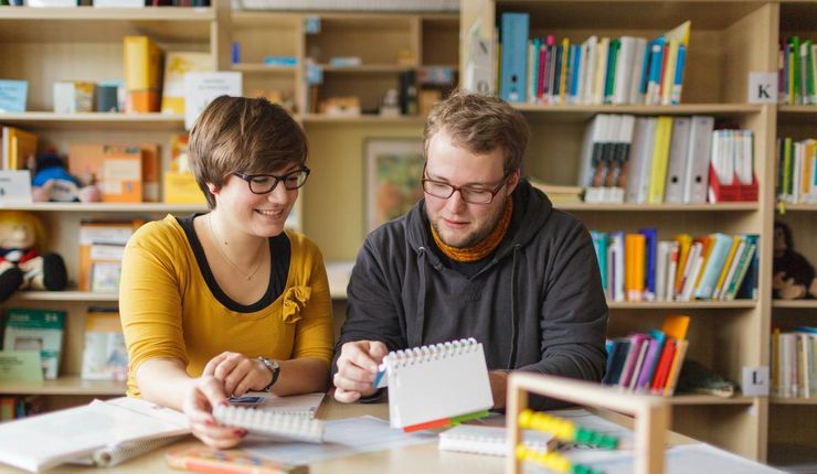 Zwei Studierende sitzen an einem Tisch und lernen.