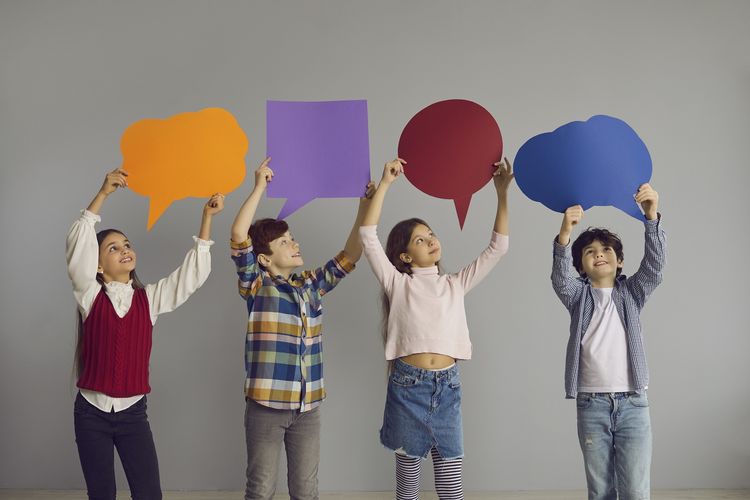 Farbfotografie von vier Kindern, die Sprechblasen in die Luft halten