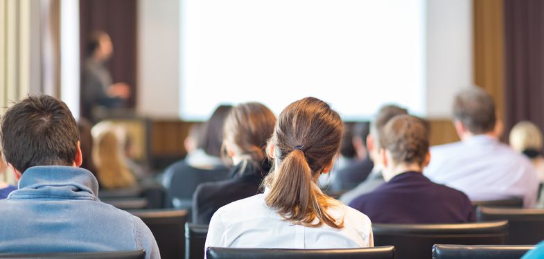 Mehrere Personen sitzen in einem Konferenzraum und hören sich eine Präsentation an, Foto: Colourbox