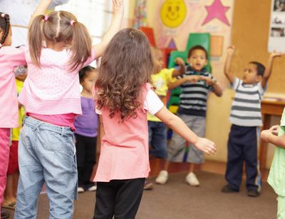 Kinder in einem Kreis in der Kita, die tanzen