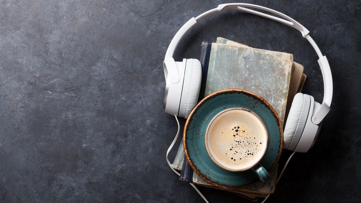 Kaffeetasse auf Bücherstapel und Kopfhörer
