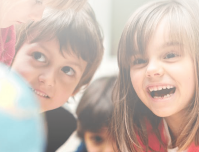 Lachende und interessierte Kinder vor einem Globus-Modell.