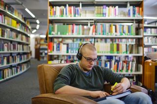 In der Bibliothek der Uni Leipzig sitzt eine studentische Person und liest etwas.