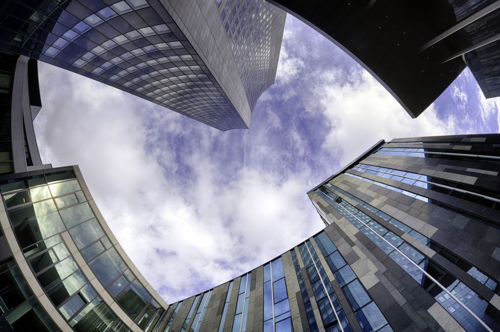 zur Vergrößerungsansicht des Bildes: Blick vom Campus Augustusplatz in den Himmel. Das futuristiche Augusteum, der Uniriese und das Gebäude der Mensa reihen sich kreisförmig um den blauen Ausschnitt des Himmels herum.