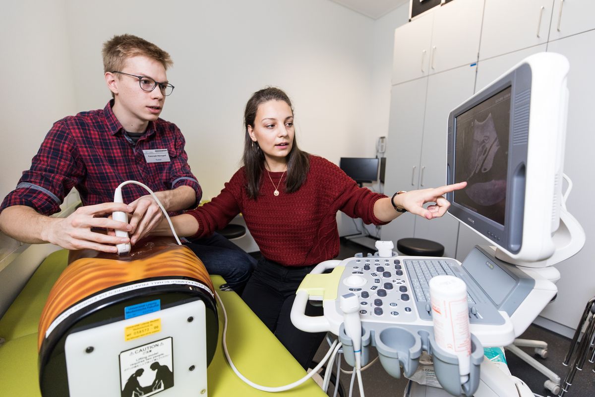 zur Vergrößerungsansicht des Bildes: Studentin erklärt Auszubildendem ein Ultraschallgerät