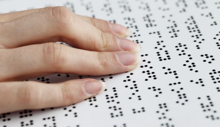 Eine Person liest ein Blatt in Braille-Schrift.